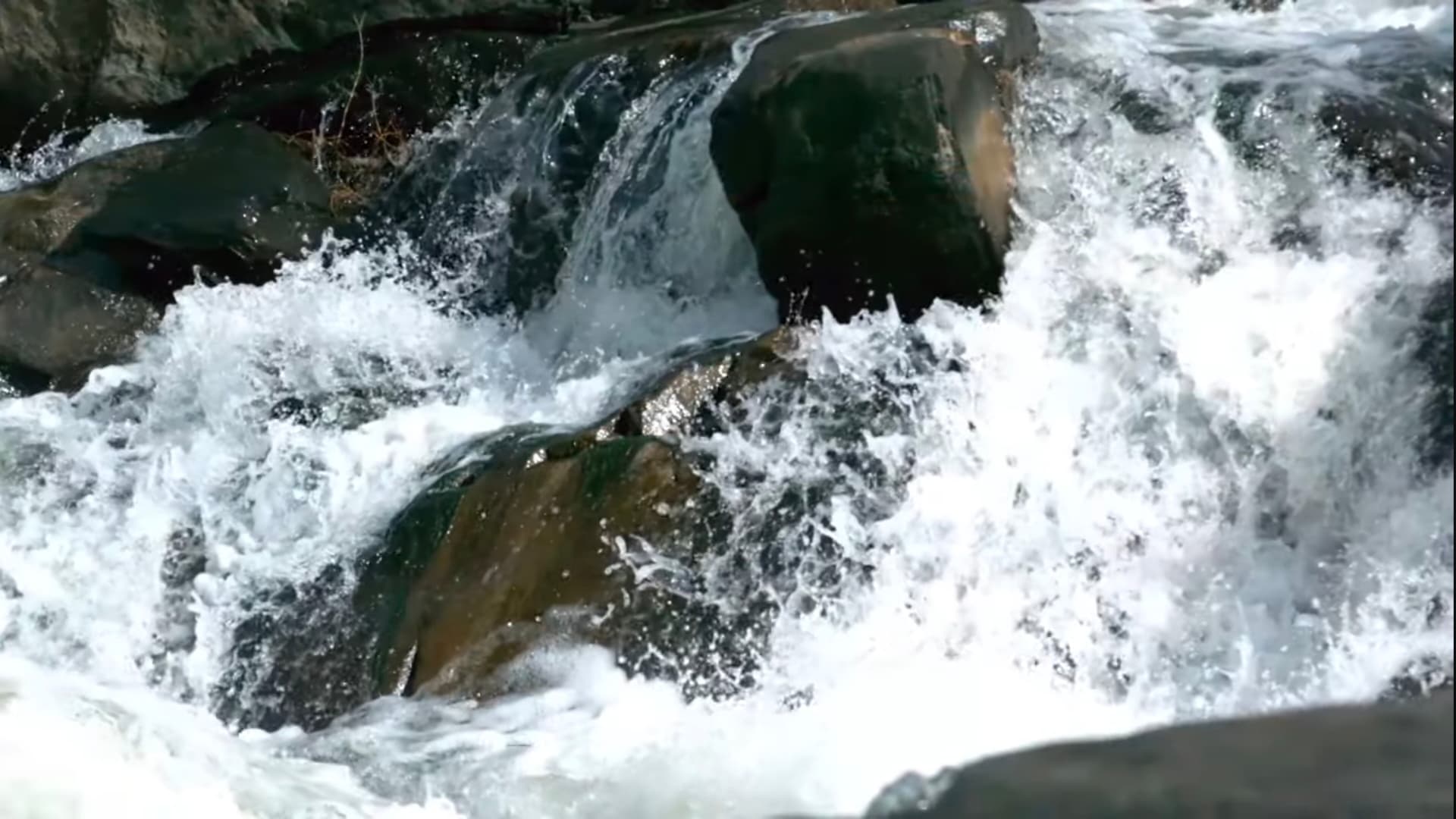 Wild waters rush fiercely over ancient rocks, creating a mesmerizing symphony of nature's raw, untamed power and endless energy. ๐